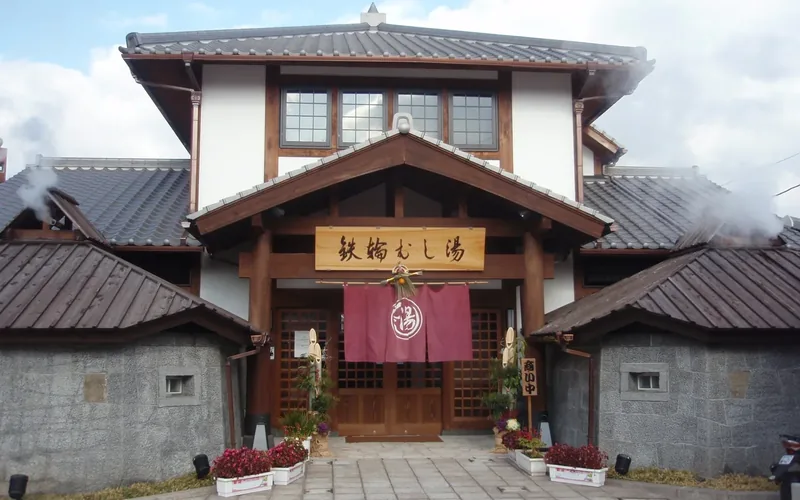 Traditional wooden entrance of Kannawa Mushiyu with steam rising from the roof