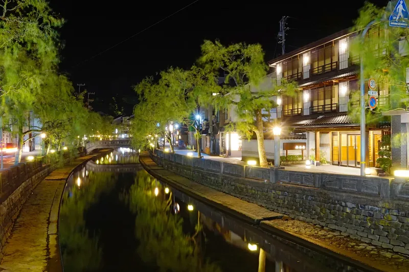Lights from riverside buildings reflecting in the Otani River at night in Kinosaki Onsen