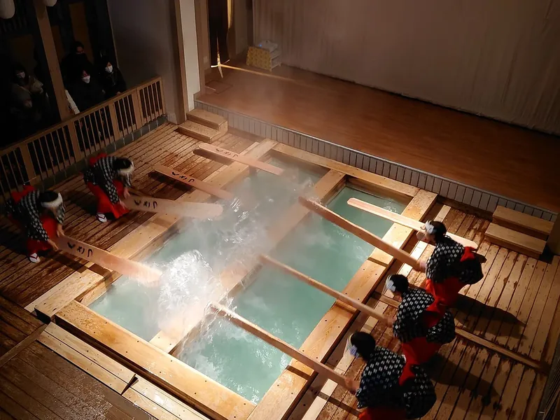 Performers stir the hot spring with long wooden paddles during a yumomi demonstration at Kusatsu Onsen